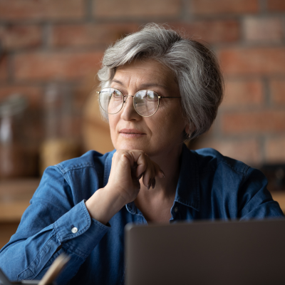 Woman over 50 sitting in front of a computer pondering her health issues.