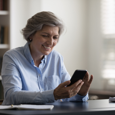 mature-woman-smiling-as-she-looks-at-her-holistic-health-program-on-her-phone.